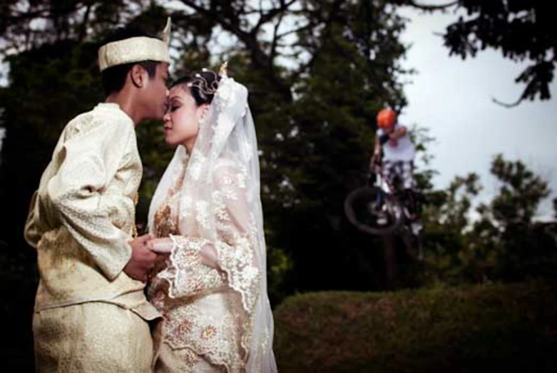 the bride and groom are kissing in the park