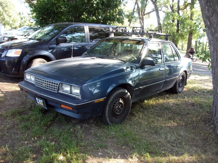 a parked car sits on the grass near other cars