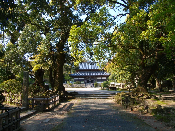 a park area with a walkway leading through a pavilion and trees