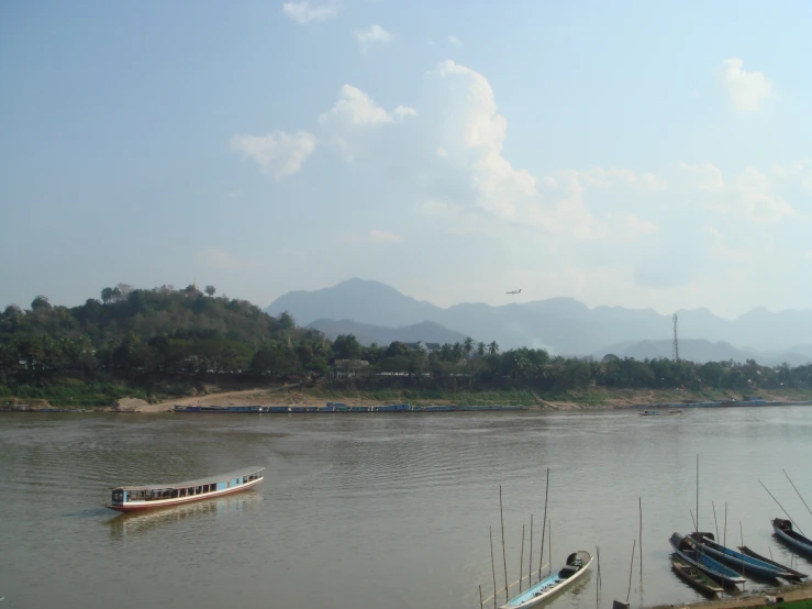 a river filled with boats next to mountains