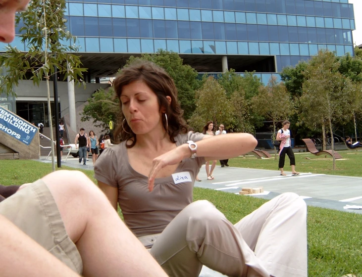 a woman is sitting on the grass using her cell phone