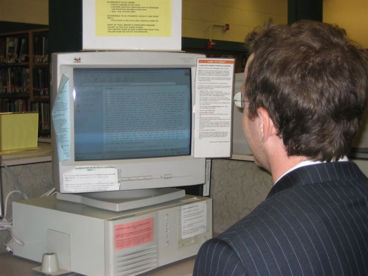 a man looking at a computer screen with many notes
