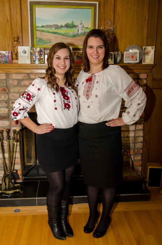 two women pose for the camera near the fireplace