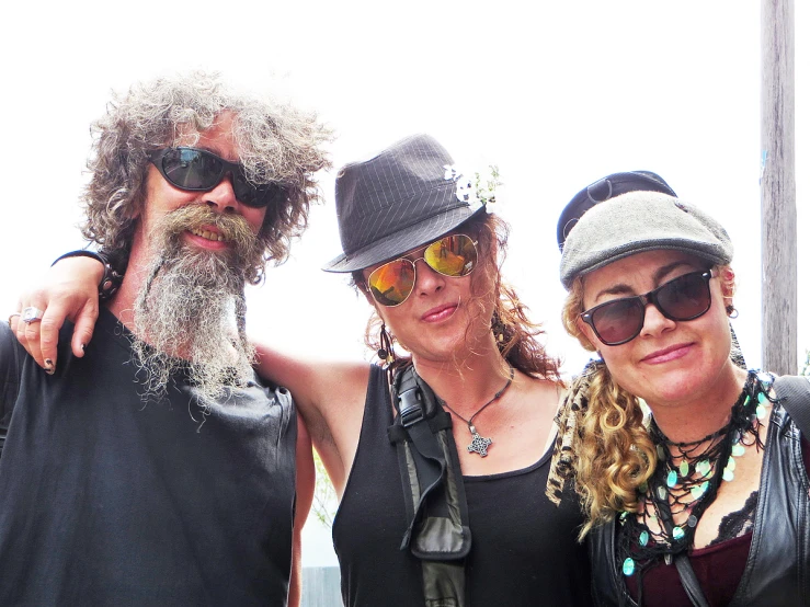 three people pose for the camera, one in sunglasses and the other with a long beard