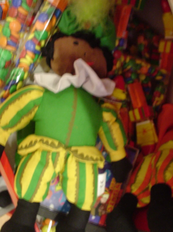 a small stuffed toy clown with a wig sits in the corner of a pile of gift wrappings