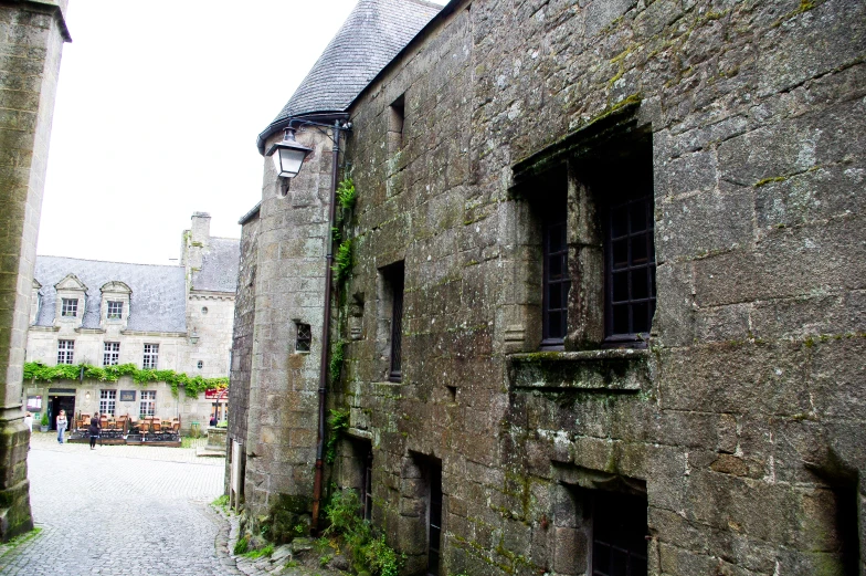 a cobblestone pathway is between a stone building