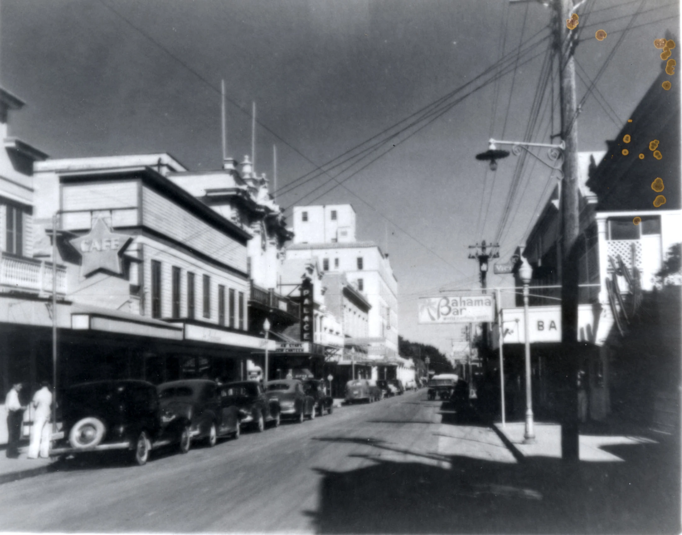 a black and white po of old cars parked in front of an apartment building