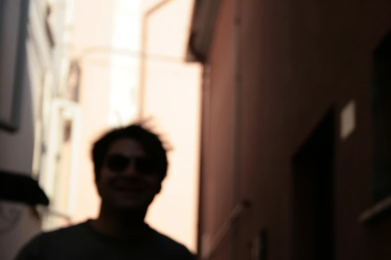 a man in grey shirt smiling on street next to building