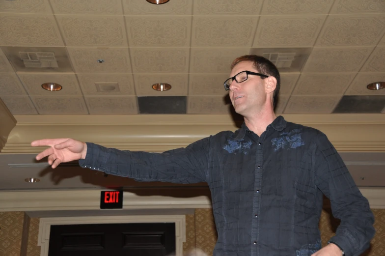 man with dark hair and glasses standing in front of an event