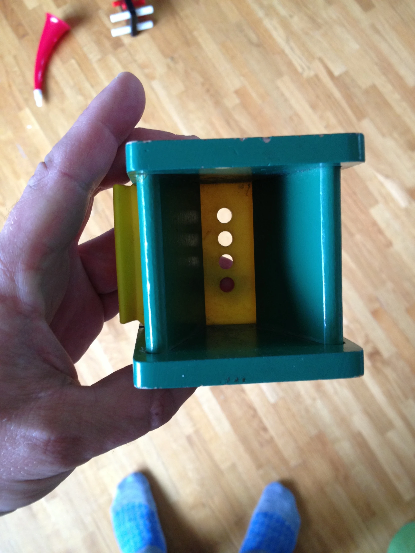 a hand holding a plastic green and yellow box