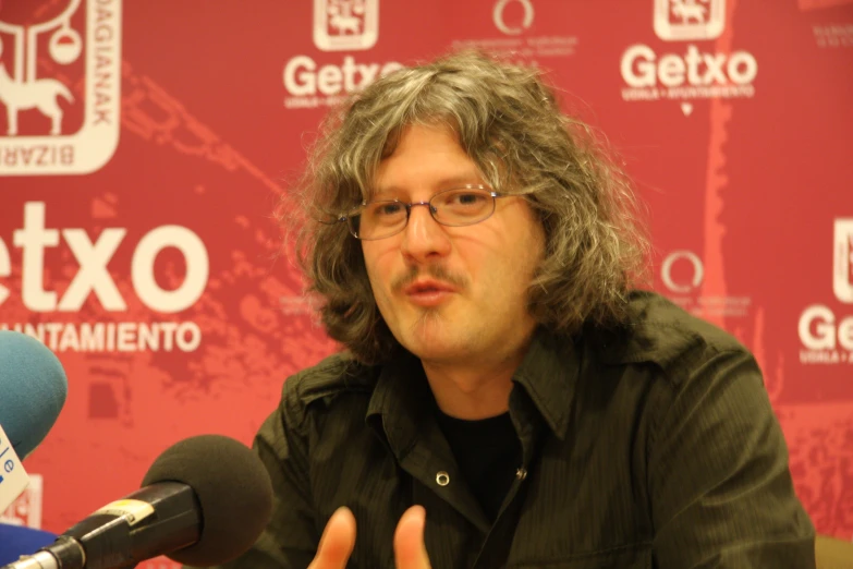 a man sitting at a press conference with microphones