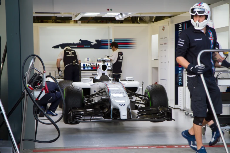 a man standing next to a race car on a garage floor