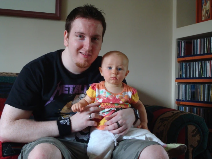 a man sitting down holding a baby with no shoes on