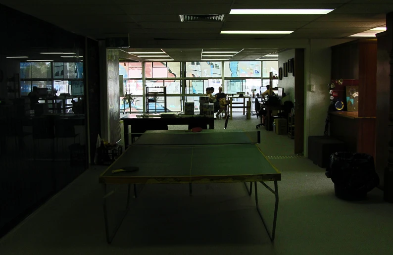 a ping pong table in a room with many windows