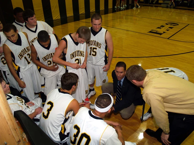 two coaches are talking to young basketball players