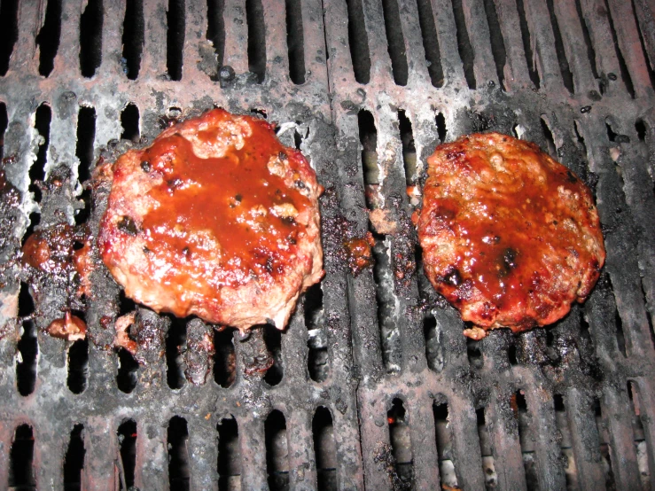 two burgers being cooked on top of a grill