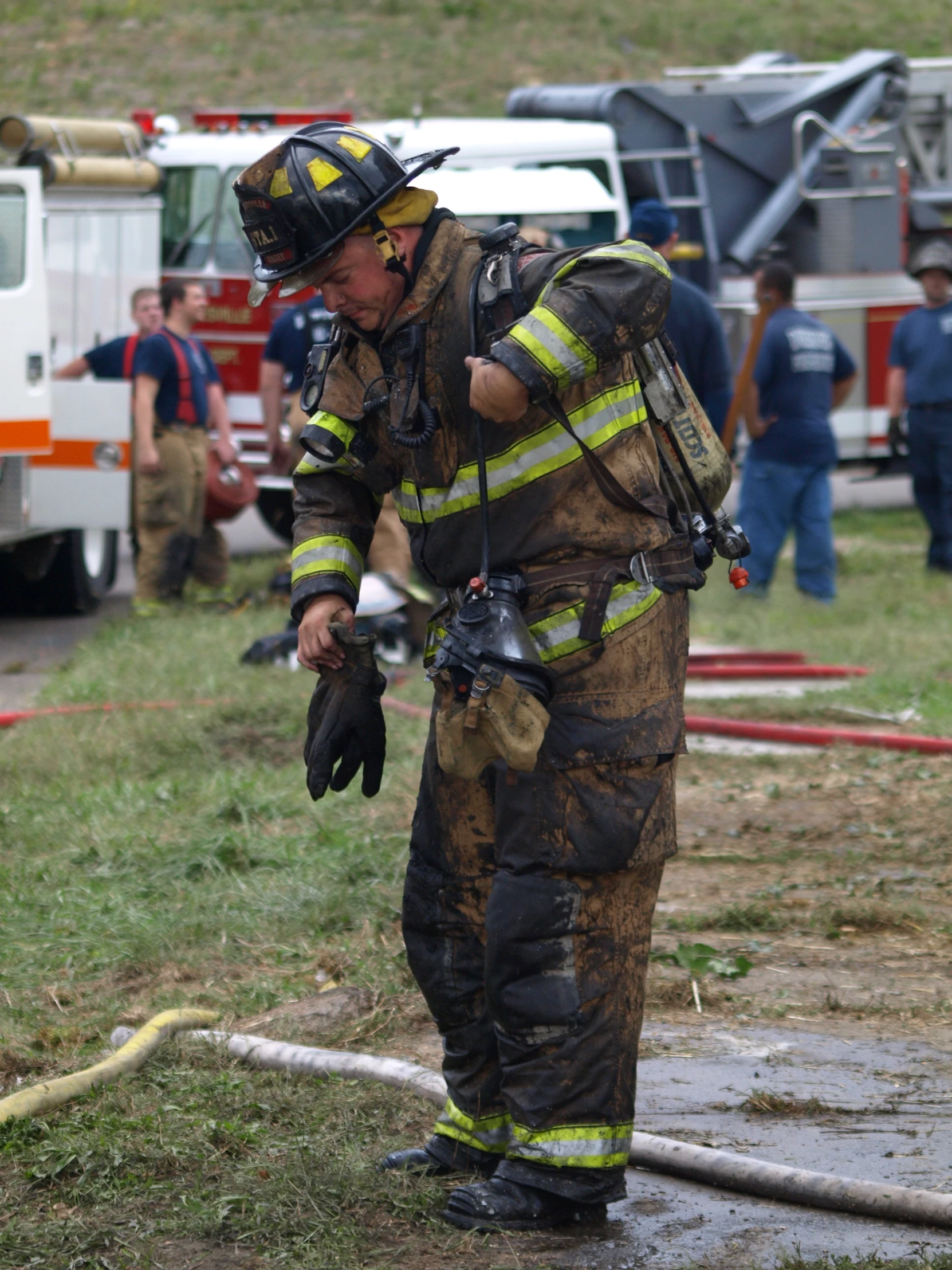 a firefighter stands in front of a hose as he adjusts his fire helmet