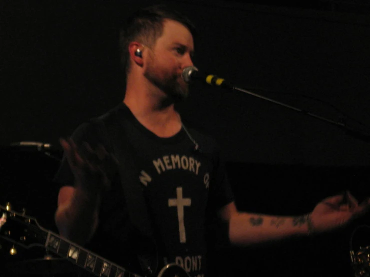 a man with a guitar and mic next to a microphone