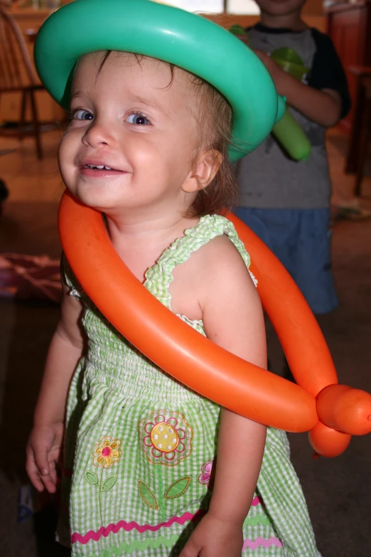 a baby girl smiles while holding a large orange balloon