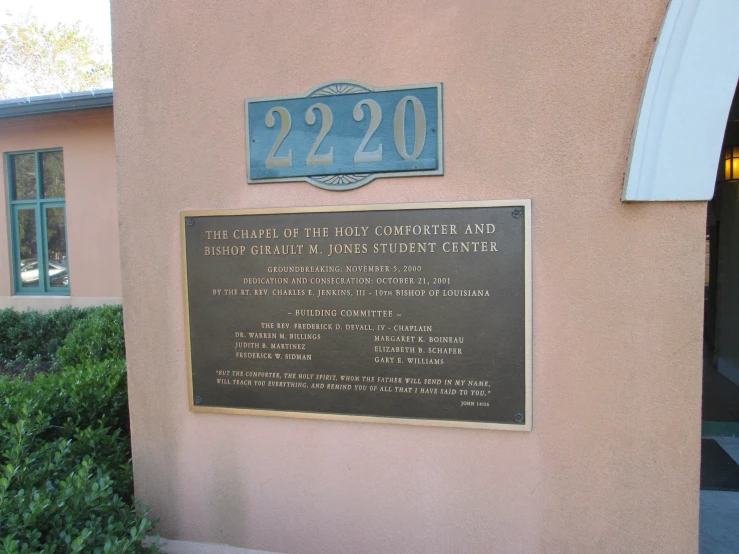 plaque on the side of a building near bushes