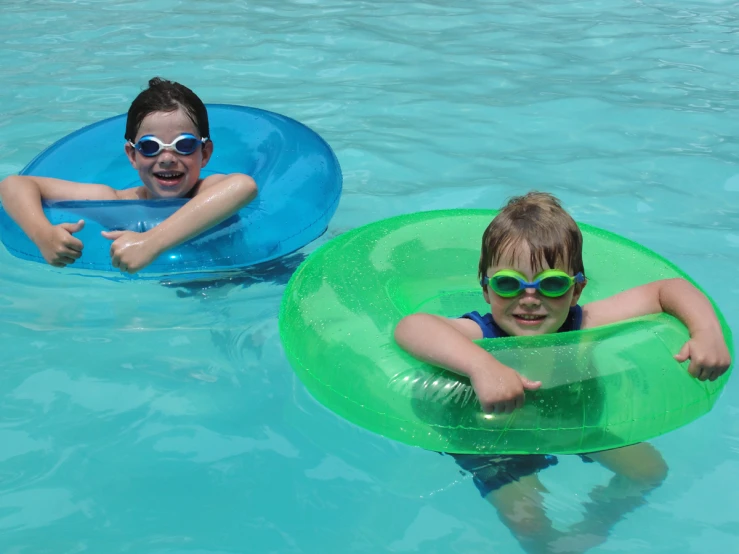 two children with glasses floating on inner tube swimming