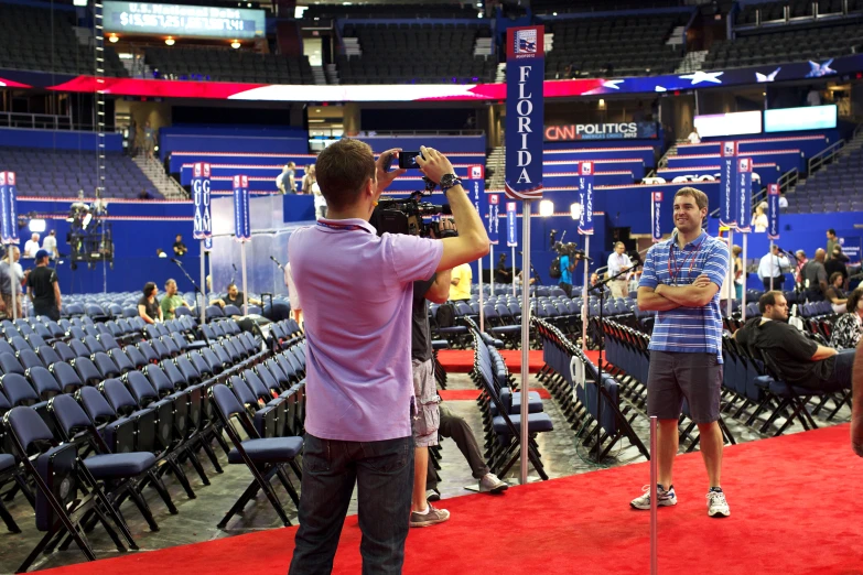 a man holding a camera in front of another person on a stage