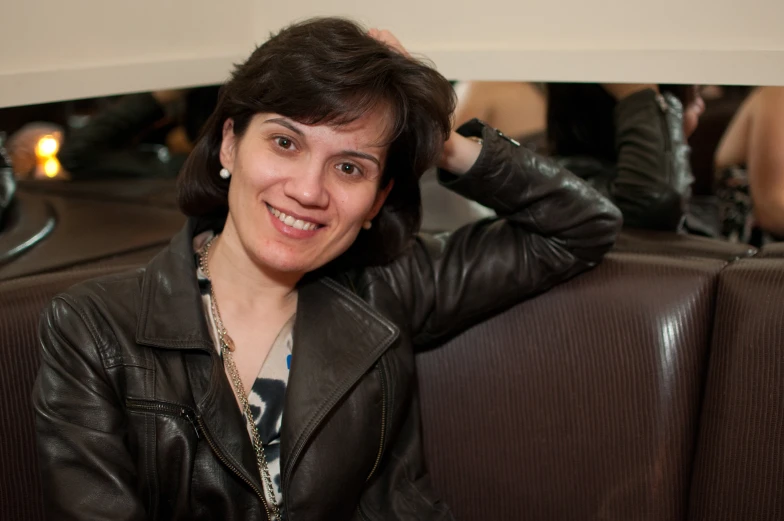 a woman smiling while she sits on the seat of a booth