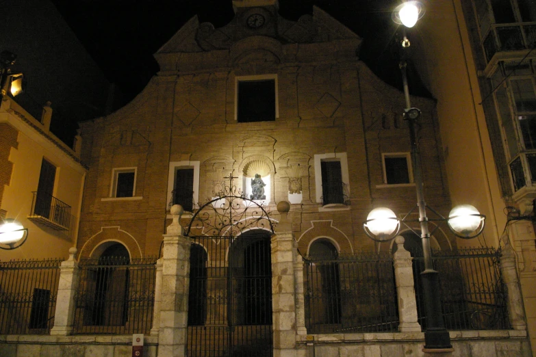 a tall building with lamps in the front and the clock on the outside