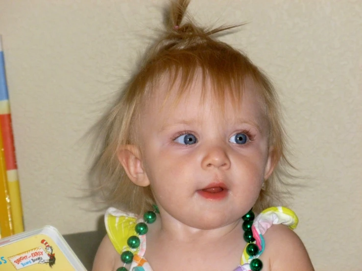 a small child with blue eyes wearing a green necklace