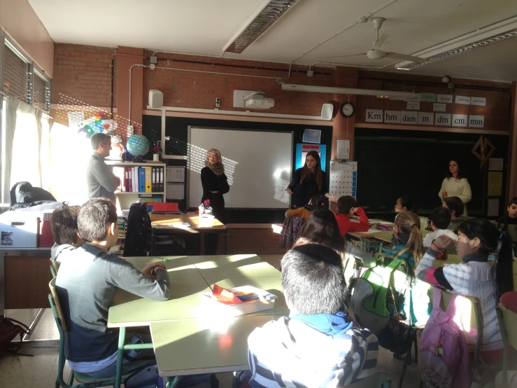 children are gathered in a classroom looking at an adult