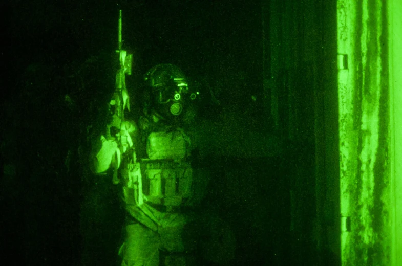 an army member is holding his rifle while standing in a green room