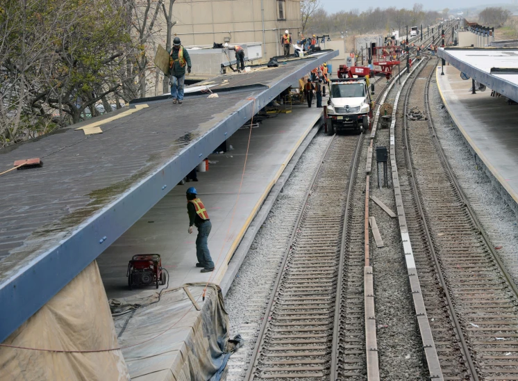 several men near a train depot working on the track