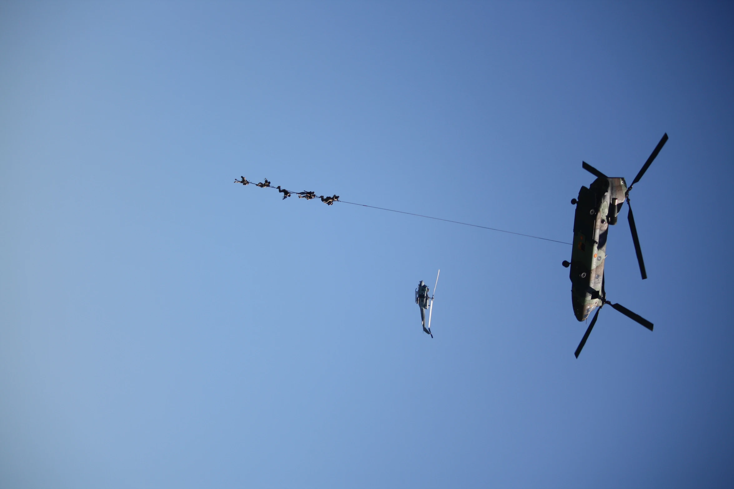 military helicopter and soldiers being pulled by helicopter