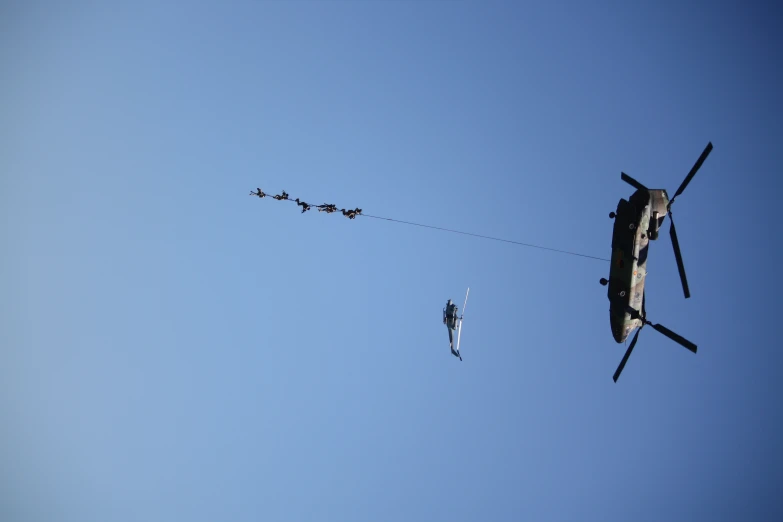 military helicopter and soldiers being pulled by helicopter