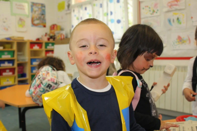 a boy in a yellow rain coat smiles at the camera