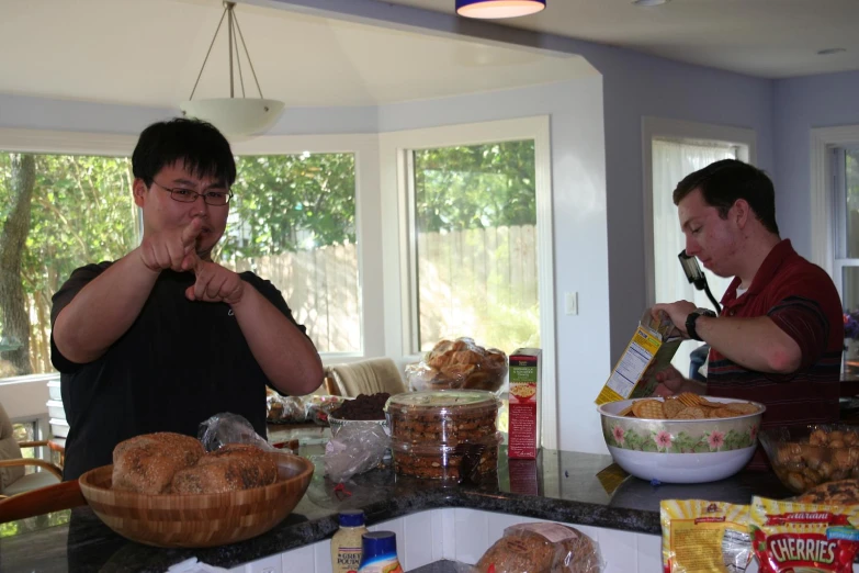 two men standing in a kitchen making food