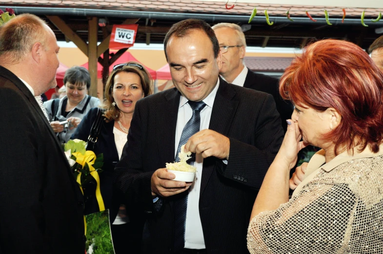 a man standing next to a woman and eating a piece of cake