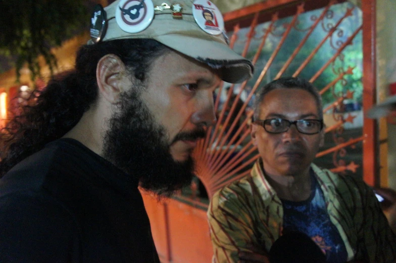 two people standing next to each other with a hat on their head