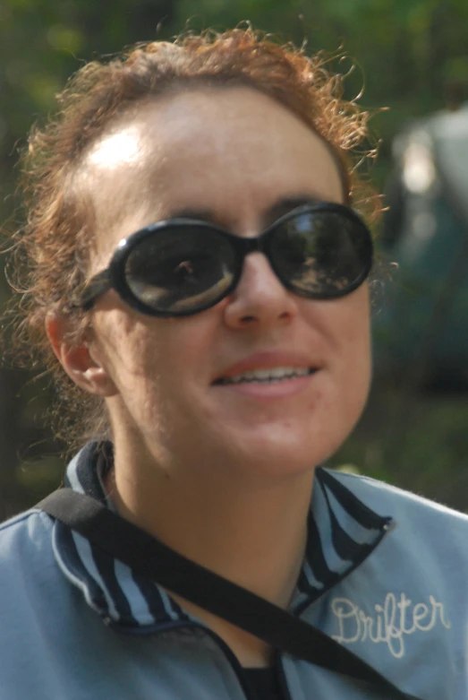 a woman wearing sunglasses and smiling at the camera