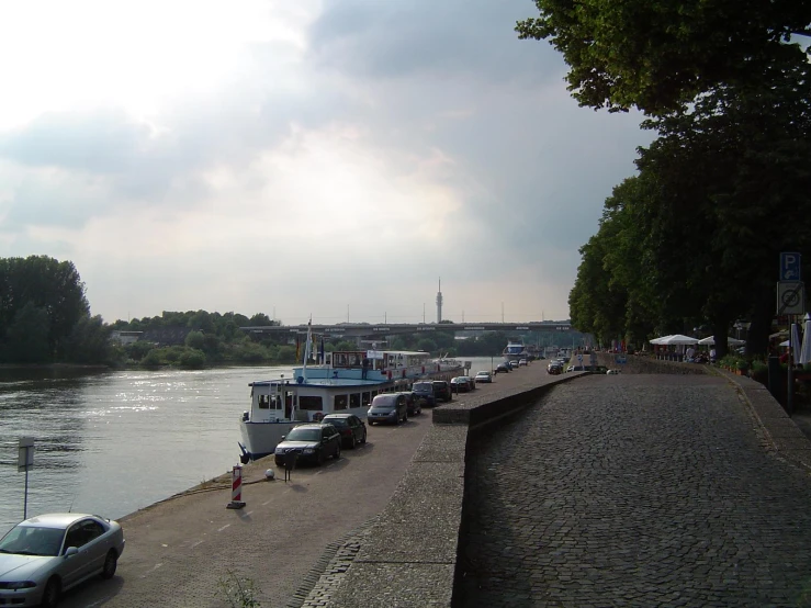 vehicles parked on side of water with city in the background