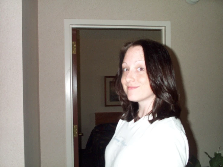a woman in a white shirt smiling in front of a door