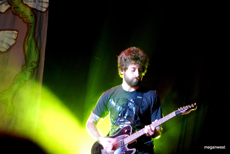 a man playing a guitar at a concert with green lights