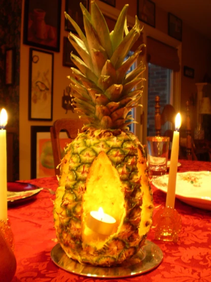 a large pineapple sitting next to a candle on a table