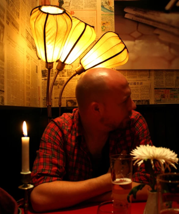 a man sitting at a table next to a vase with flowers