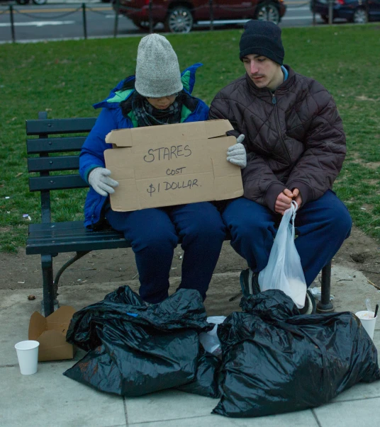 two people holding sign on the bench during winter