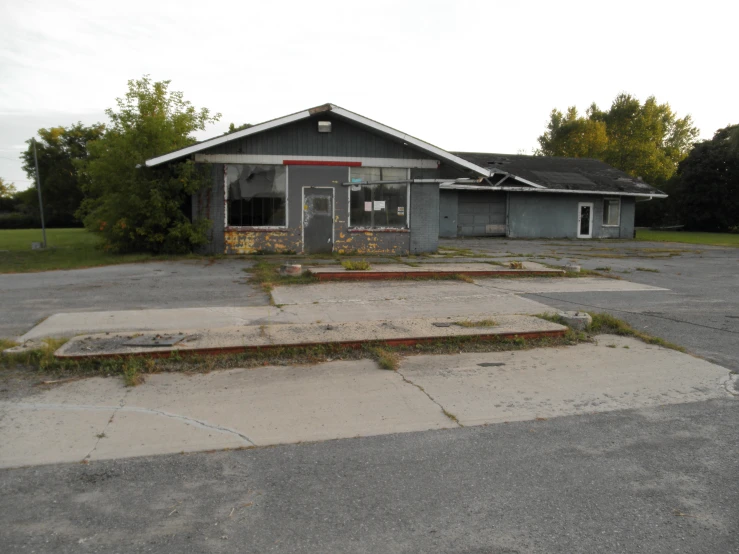 a rundown building with an overhanged porch and steps leading to a doorway