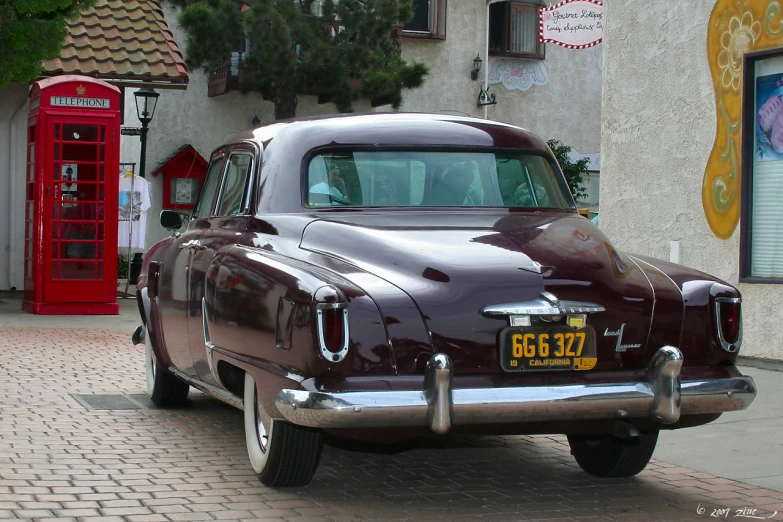 an old fashion car is parked in front of a shop