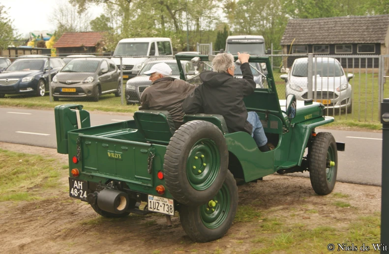 a green truck on a dirt road with some people driving in it