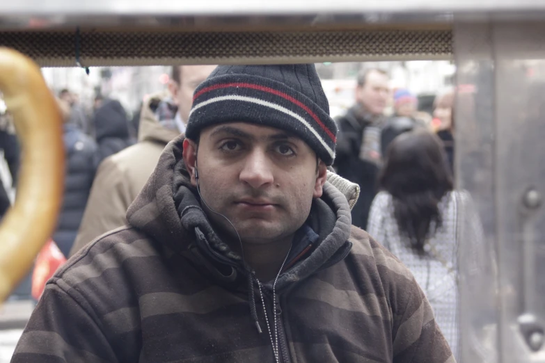 a man wearing a hat and brown jacket looks up into the distance