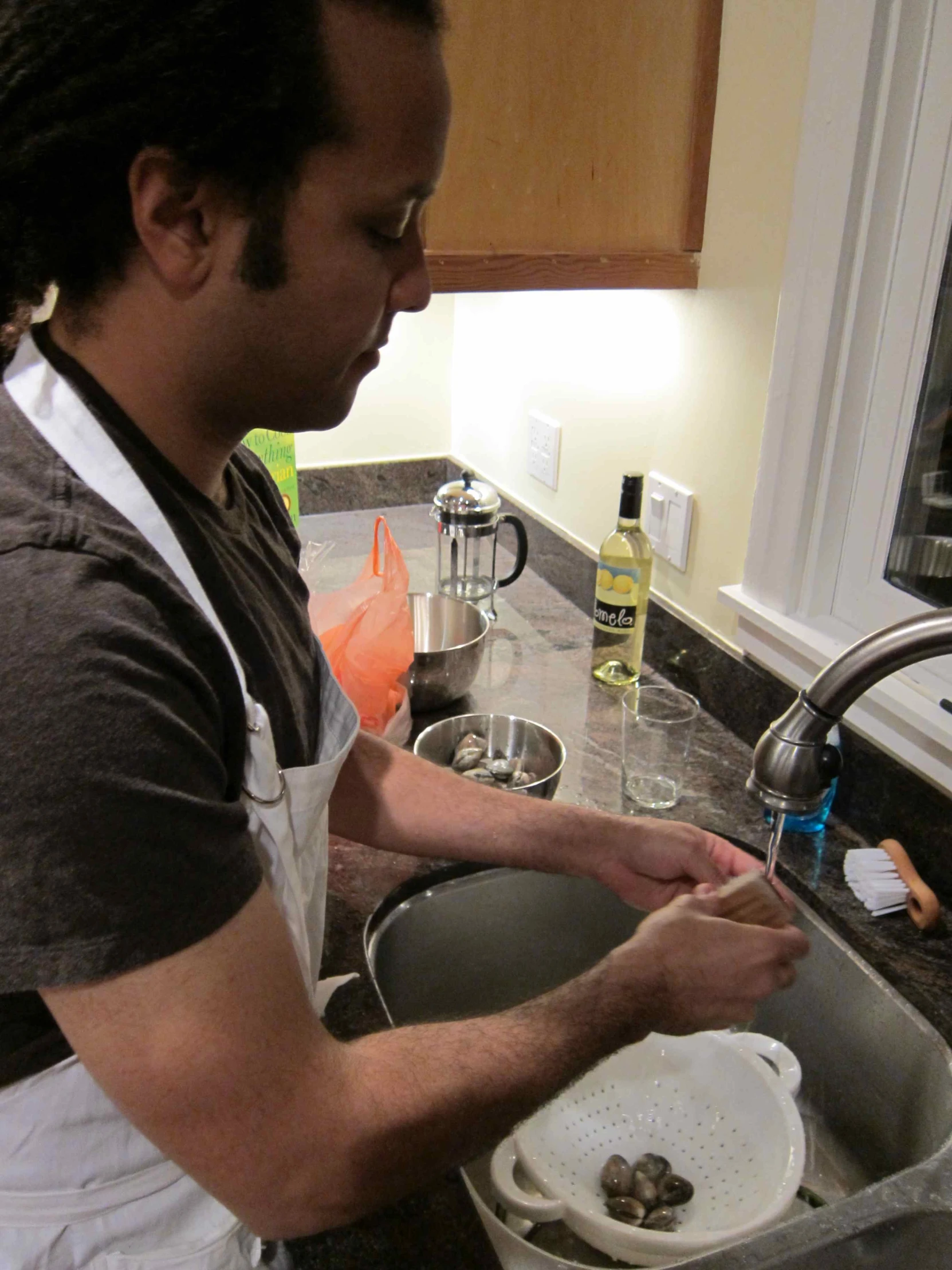 a man wearing an apron washing his hands in the sink